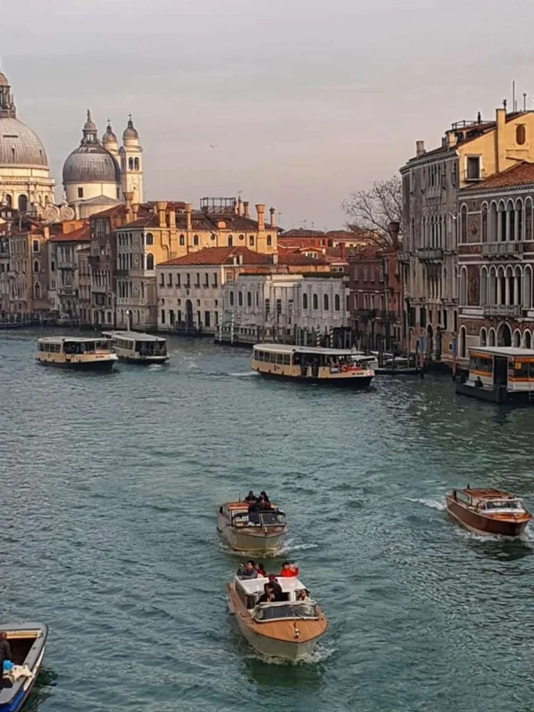 A canal in Venice lined with historic buildings and water buses, a destination that can be calmer with planned rest.