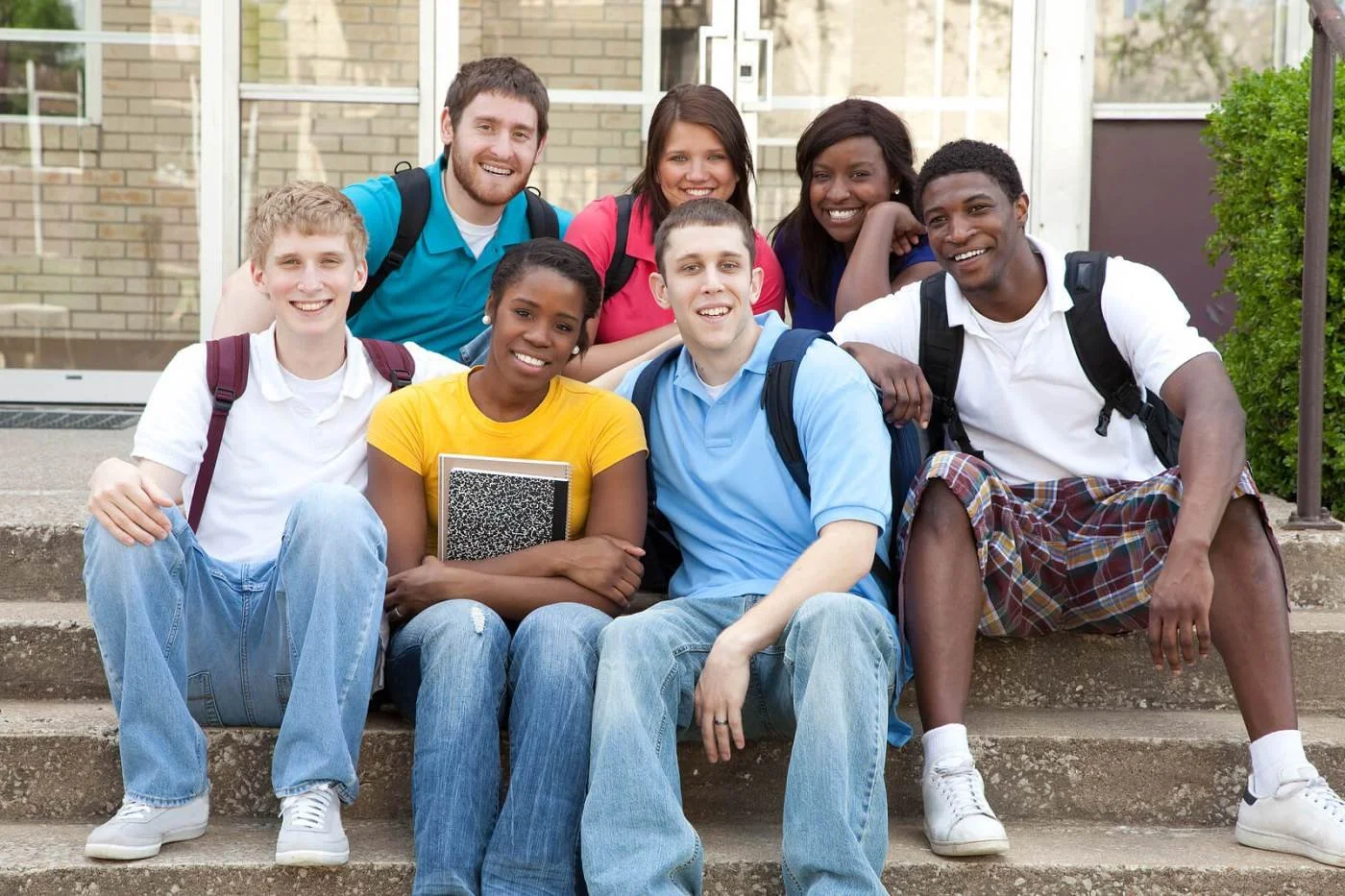 A group of college friends sitting on steps with backpacks, showing how friendship can look different for introverts.