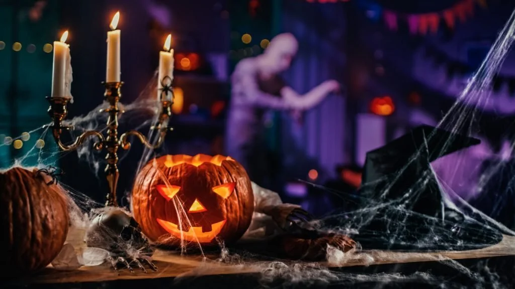 A Halloween table with a lit jack-o-lantern, candles, and cobwebs, the cozy side of spooky season for highly sensitive people.