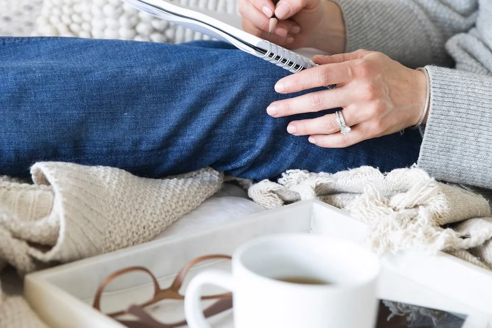 A woman’s hands writing in a notebook while seated on a blanket with a cup of tea on a tray, a calming routine for anxiety.Boundary script graphic: Acknowledge, set the Boundary, then offer a Creative Yes when a parent criticizes your choices.