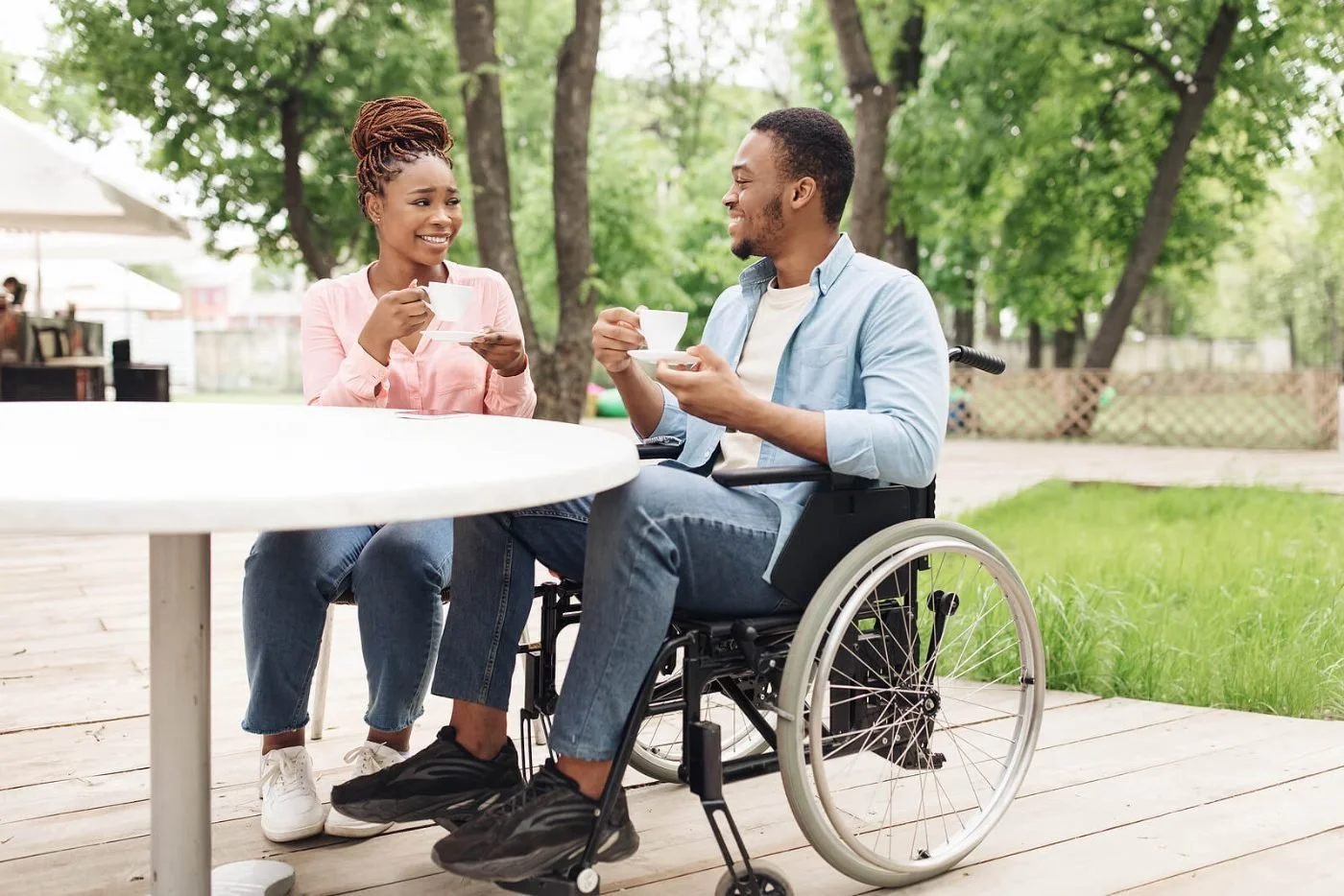 A woman and a man at an outdoor cafe table sharing a relaxed conversation over coffee, a low-risk way to connect.