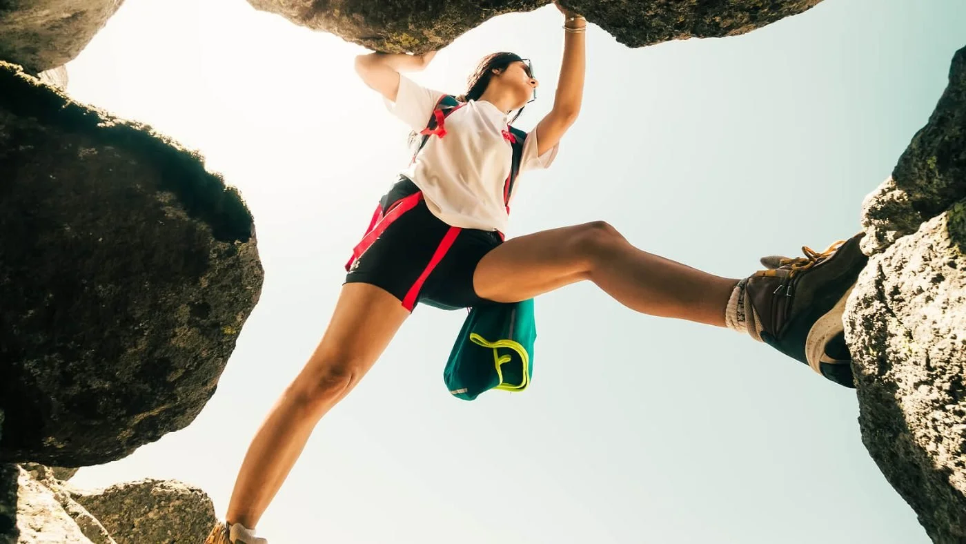 A climber reaching for a hold on a rock overhang, the kind of physical risk some highly sensitive people avoid.