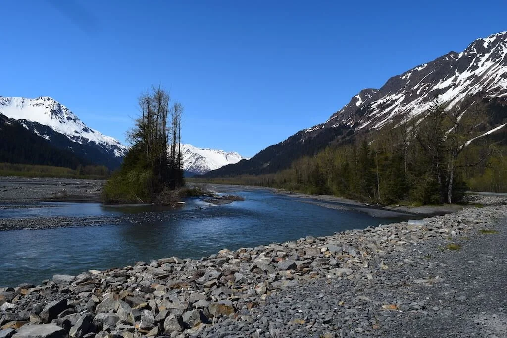 A river winding below snow-capped mountains near Girdwood, Alaska, a quiet scene from a family trip.