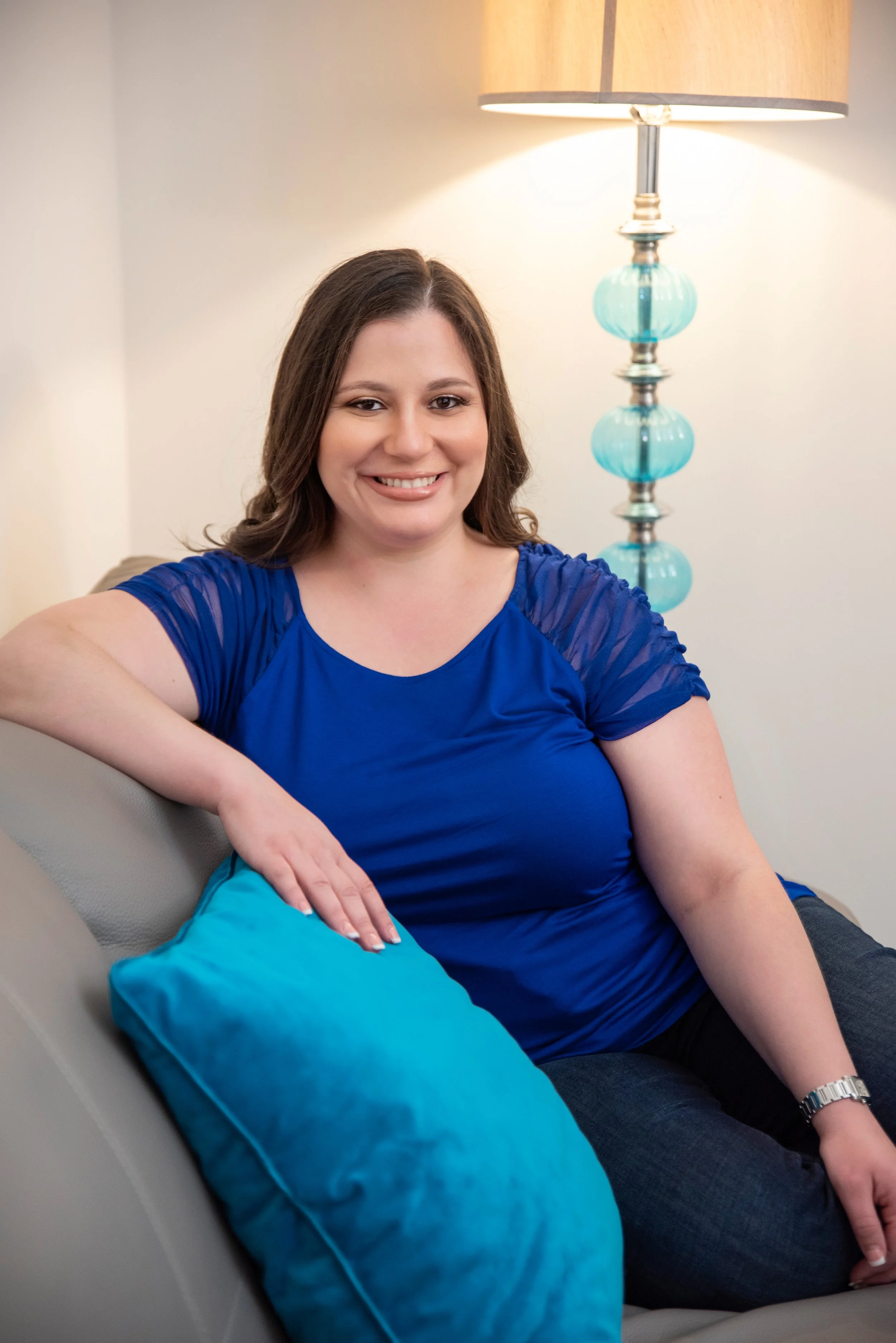 Florida online therapist Enid DeJesus sitting on a couch, looking relaxed and confident.