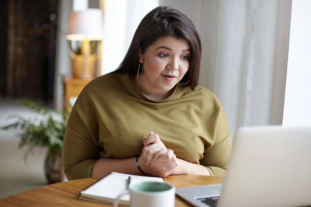A woman at a wooden table with a laptop, a notebook, and a mug, preparing for an online therapy consultation.Boundary script graphic: Acknowledge, set the Boundary, then offer a Creative Yes when a parent criticizes your choices.