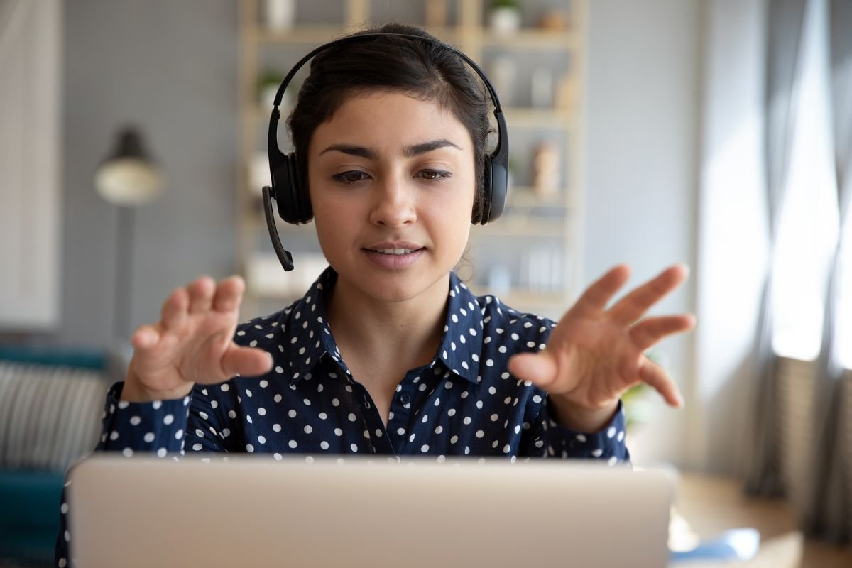 A woman wearing a headset and gesturing as she talks during a video session on her laptop.Terri Cole quote graphic: "Your job as a grown up is to set the boundaries that work for you in your adult life."