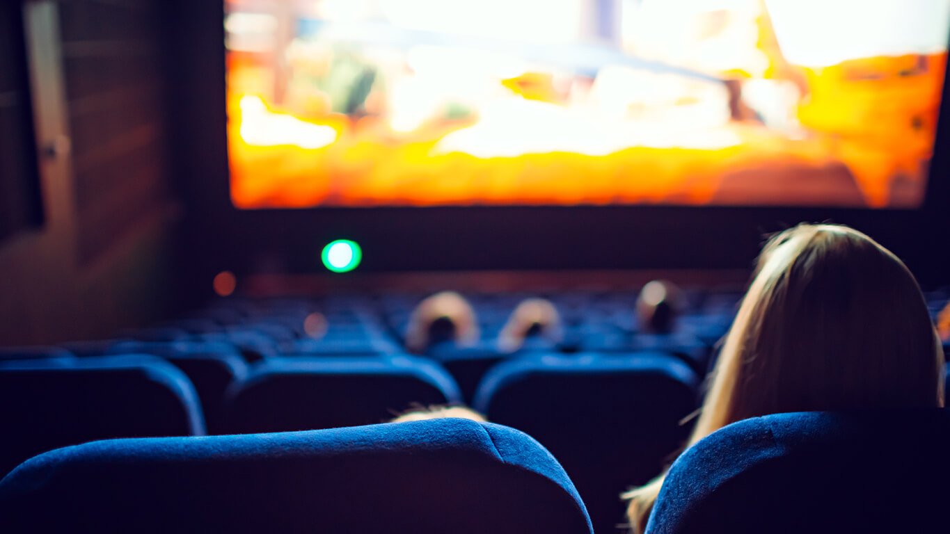 A woman in a movie theater avoiding a scary movie, as a highly sensitive woman decides what she is comfortable watching.