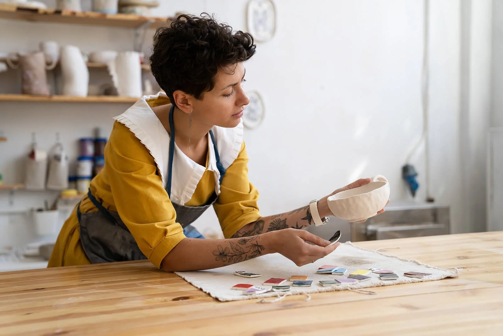 A woman with short hair working on a creative project at a wooden table, using creativity to cope with depression.