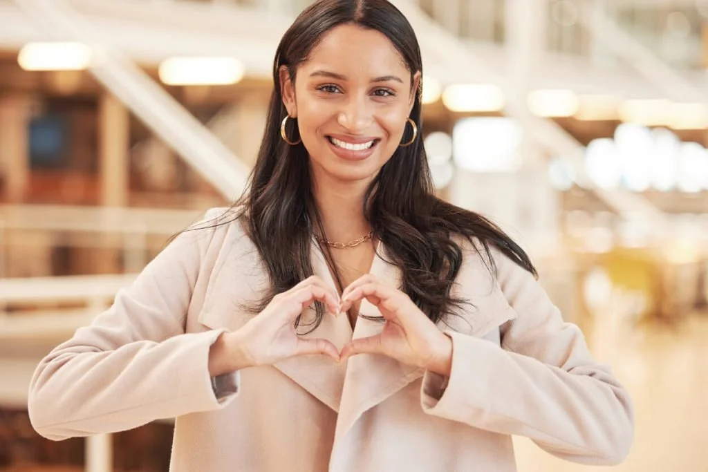 A woman holding her hands in the shape of a heart.