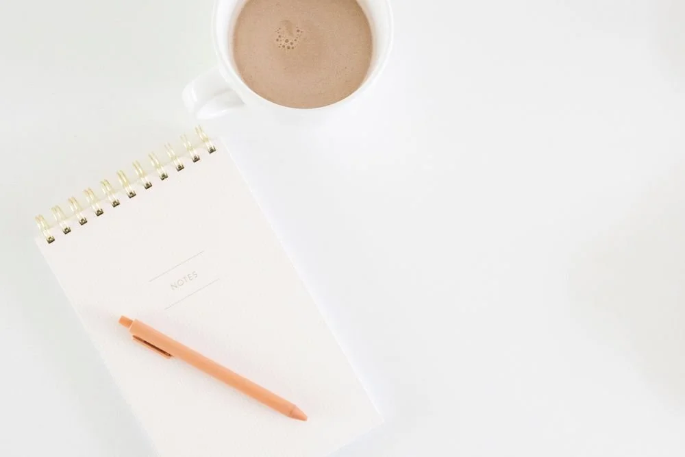 A spiral notebook, an orange pen, and a cup of coffee on a white surface, ready for a journaling session.Terri Cole quote graphic: "Your job as a grown up is to set the boundaries that work for you in your adult life."