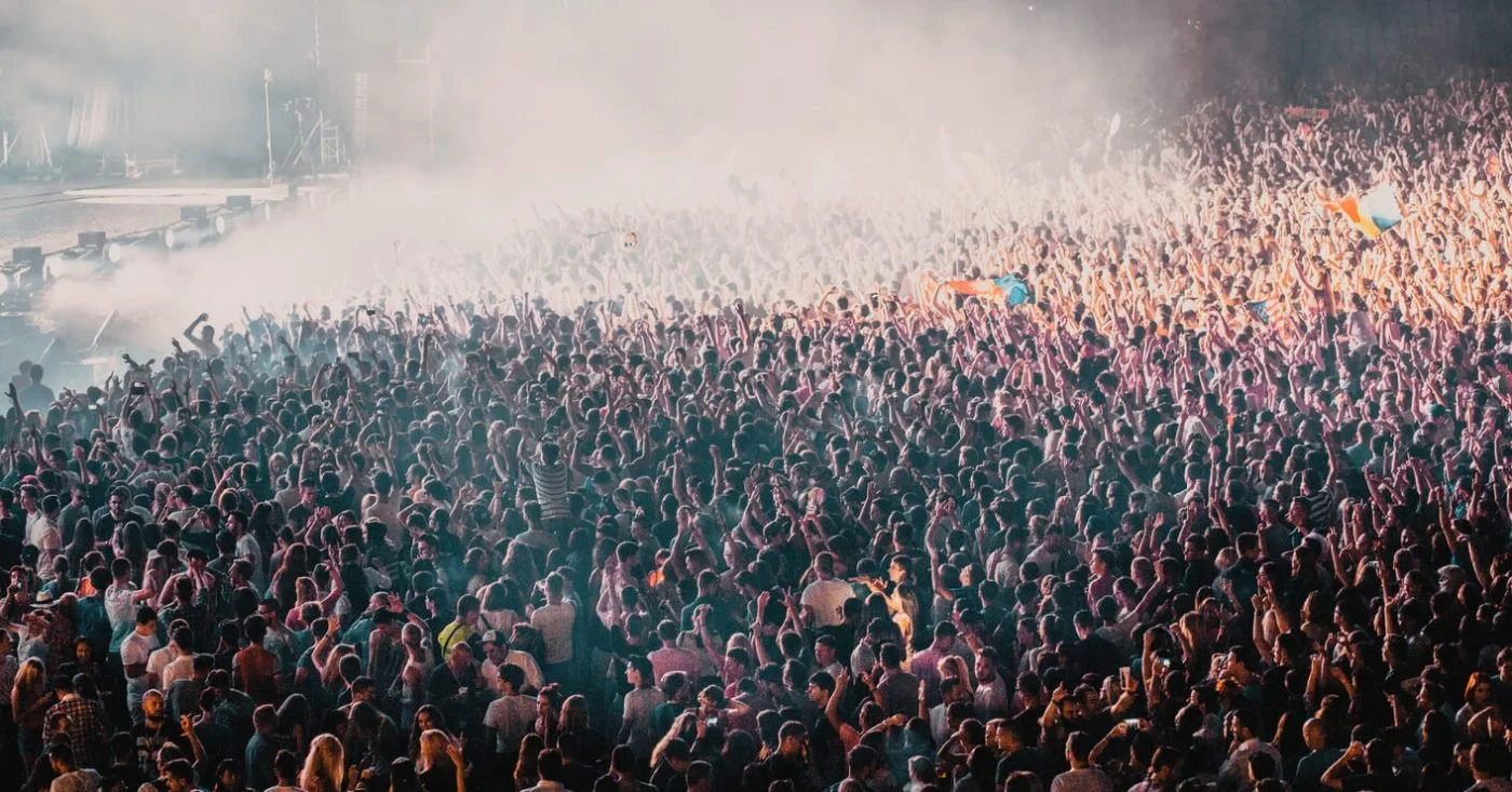 An aerial view of a large crowd at a concert at night, for highly sensitive people planning for loud, crowded events.