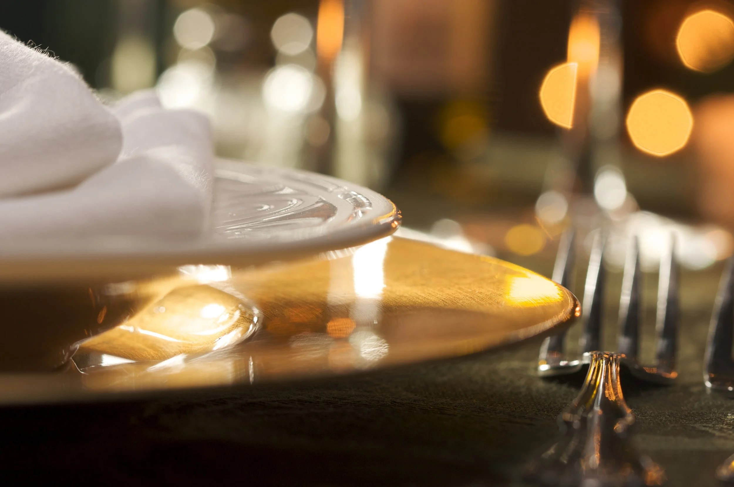 Close-up photo of shiny, empty dessert and wine glasses on a wooden surface with blurred warm lights in the background.