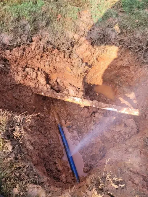 A broken black pipe sprays out water in a Cumming, GA yard.