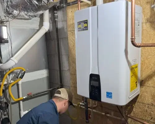 A plumber for Rx Plumbing finishes a tankless water heater installation in a basement in Suwanee, GA.