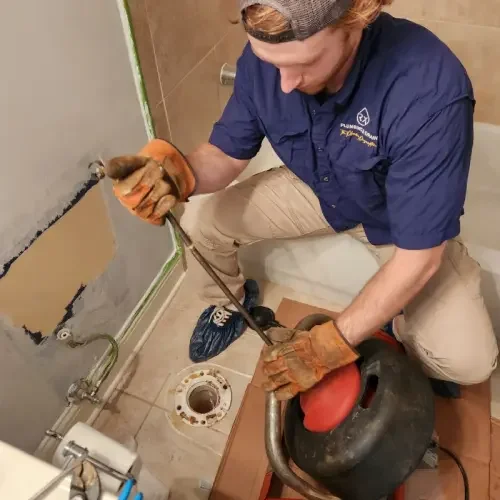 A plumber uses a commercial-grade auger to clean out a clogged toilet drain in a Cumming, GA bathroom.