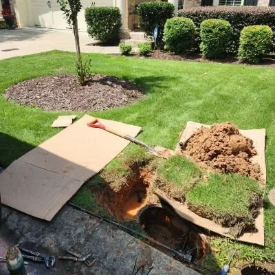 A broken pipe under a yard in Johns Creek, GA is being replaced by Rx Plumbing & Drain, with cardboard protecting the grass.