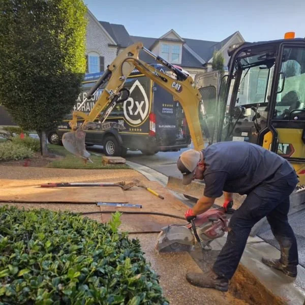 A plumber for Rx Plumbing works with an excavator and saw to repair a yard leak in Johns Creek, GA.