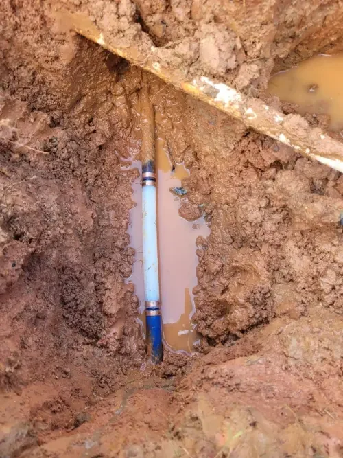 A newly repaired underground pipe with copper fittings in a Cumming, GA yard before being covered back up.
