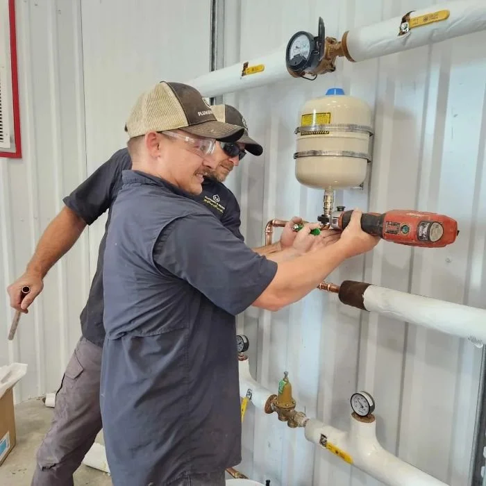 Two Rx plumbers use specialized tools to repair pipes at a commercial facility basement in Alpharetta, GA.