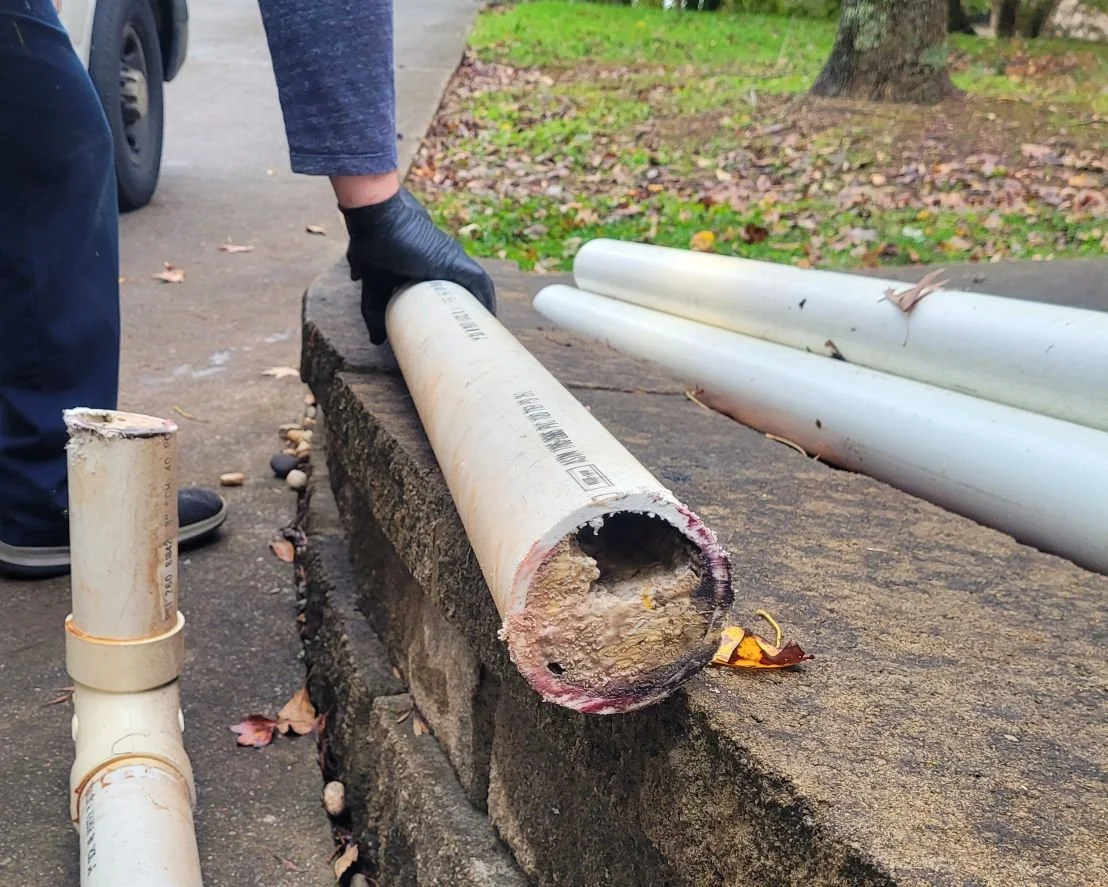 Rx-Plumbing and Drain plumber holding a section of sewer line PVC pipe that is clogged with built up sludge in Buford, Ga.
