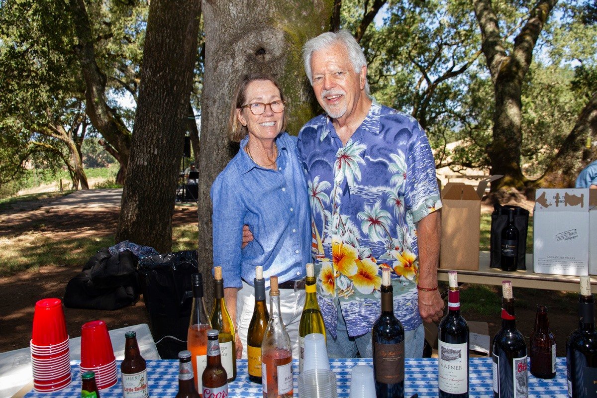 Man and woman standing behind a table of wine bottles