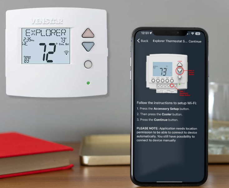 A wall-mounted digital thermostat displaying 72 degrees Fahrenheit, with a smartphone showing setup instructions for connecting a similar thermostat to Wi-Fi.