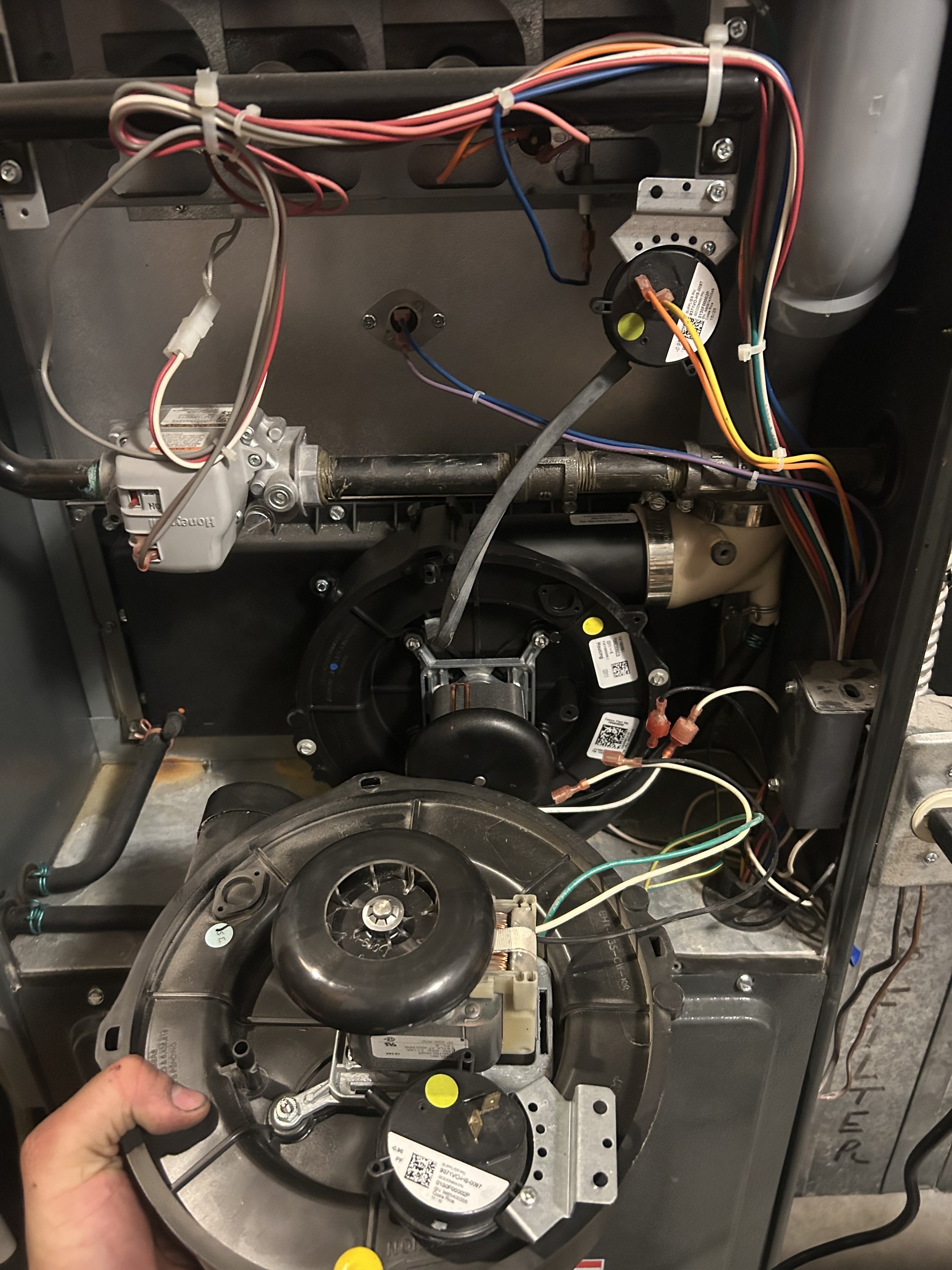 The image shows the inside of a furnace with visible electrical wiring, a blower wheel, and various components.