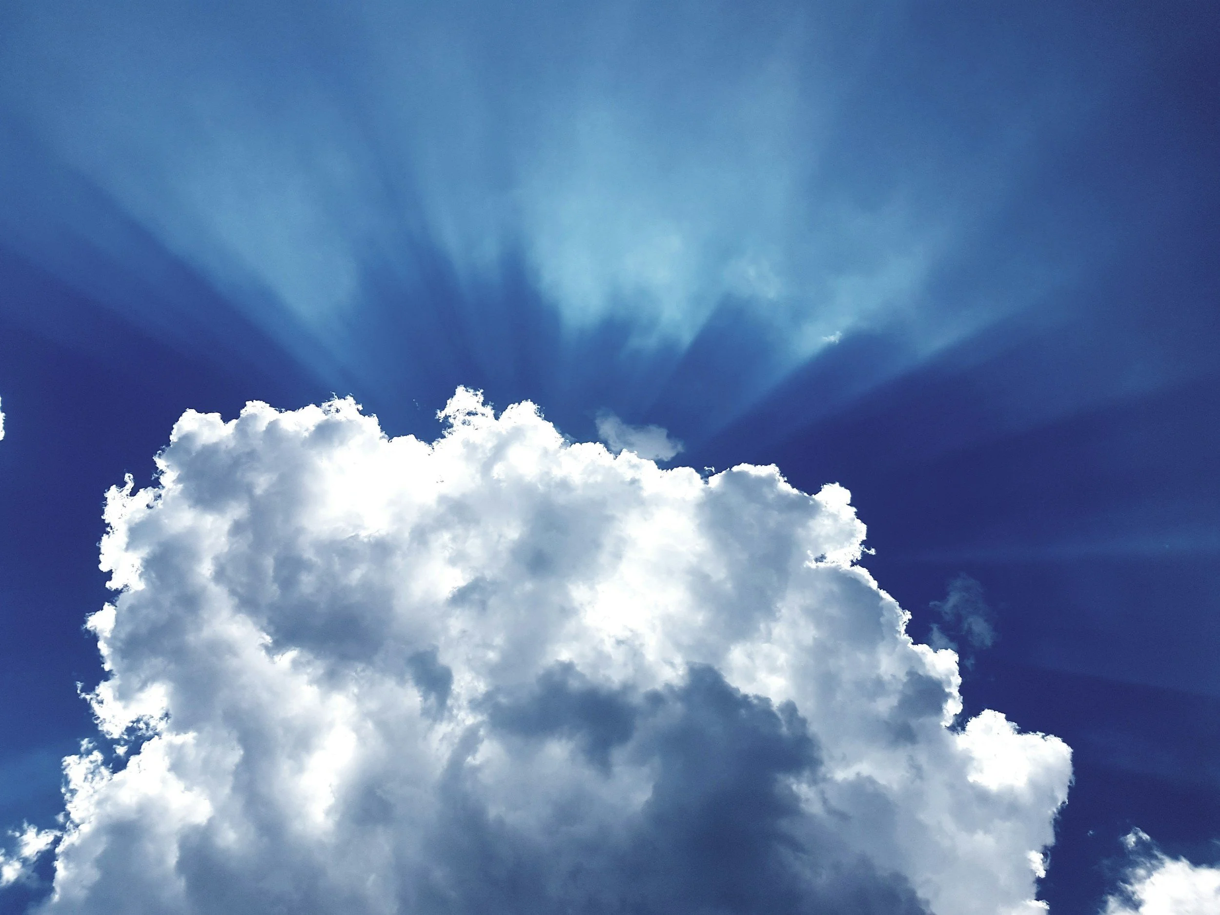 white clouds with a ray of sun appearing above it