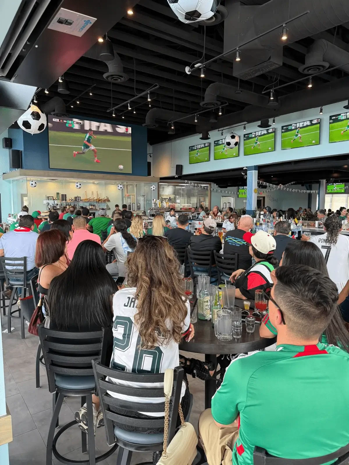 Guests enjoying live sports and a lively atmosphere at El Muelle Seafood in Houston.