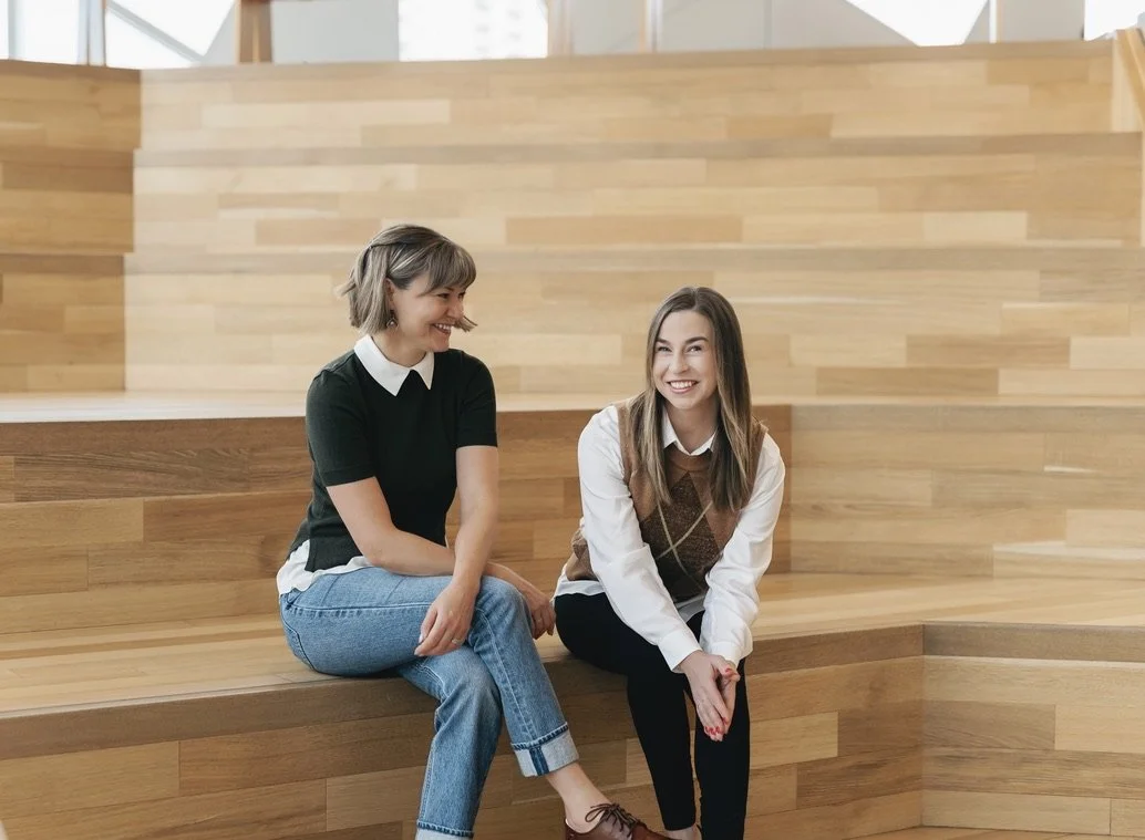 Janessa Torres and Kyla Vieweger smiling and engaging in conversation, in a well-lit indoor space. Co-owners and clinic directors of Wise Mind Therapy Collective.
