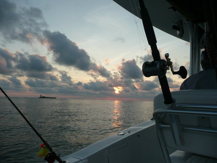 Fishing rod and reel on a boat against a cloudy sunrise
