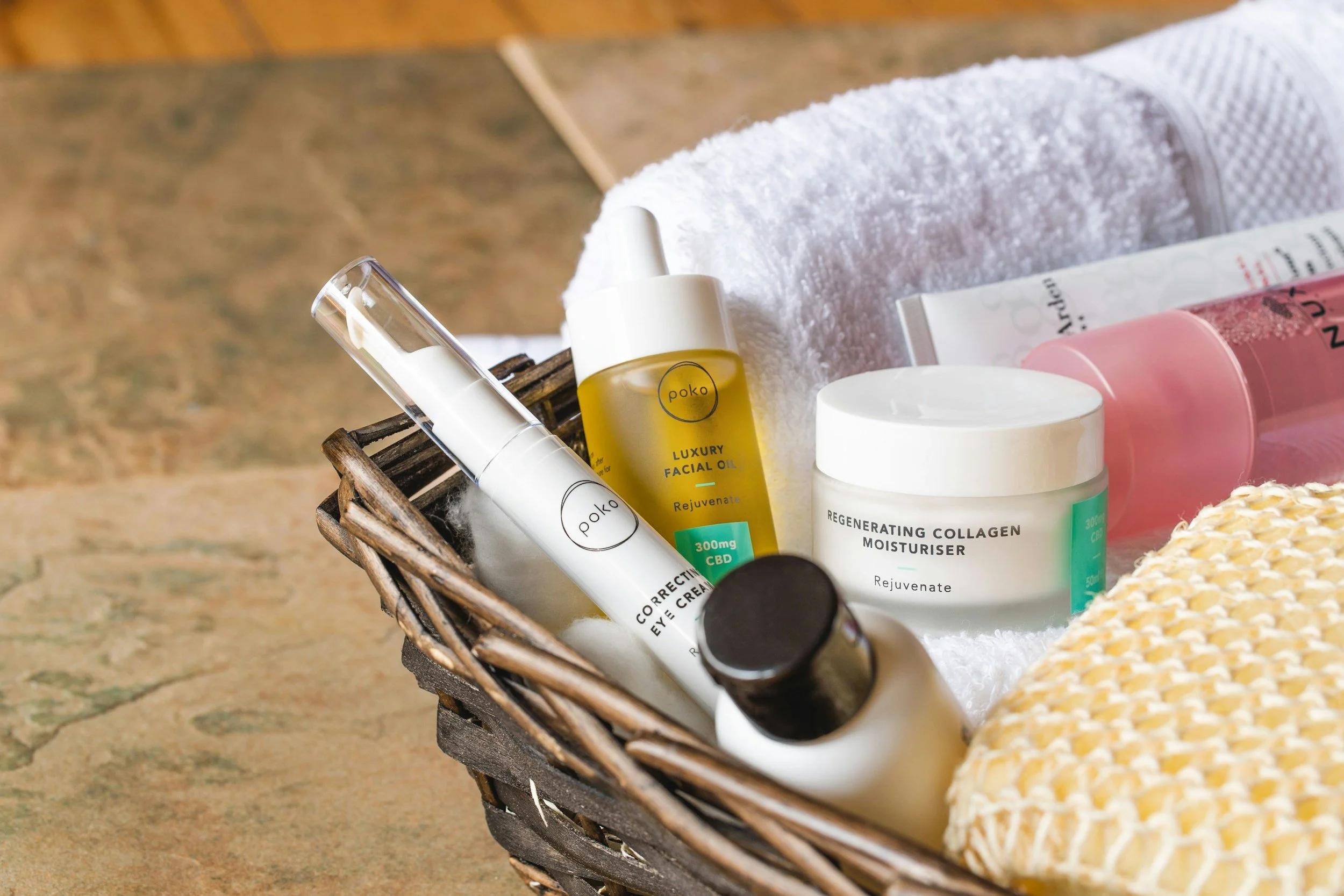 Basket containing skin care jars, tonics and tubes and a white towel