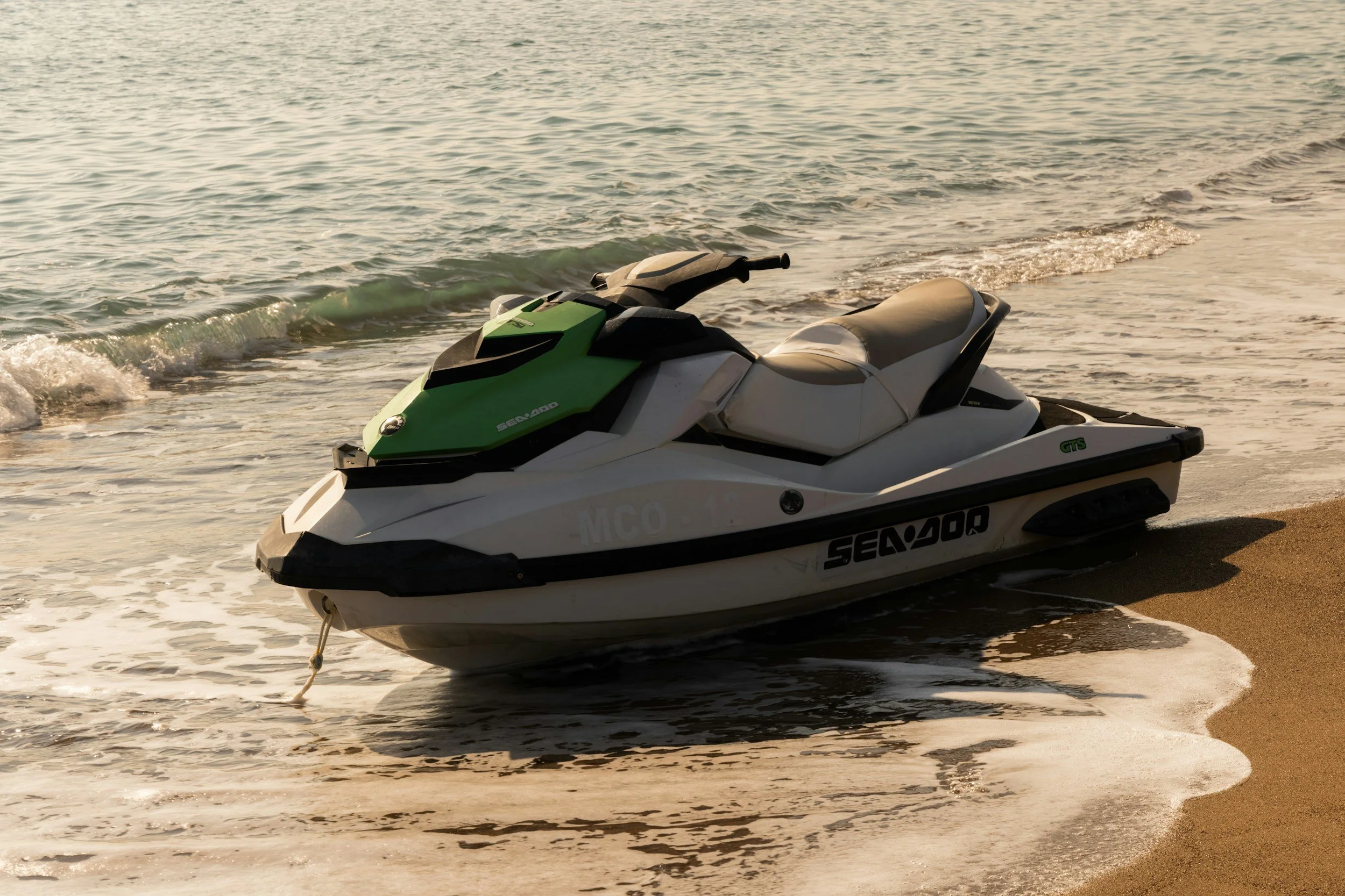 Jet ski sitting in water rolling in on sandy beach