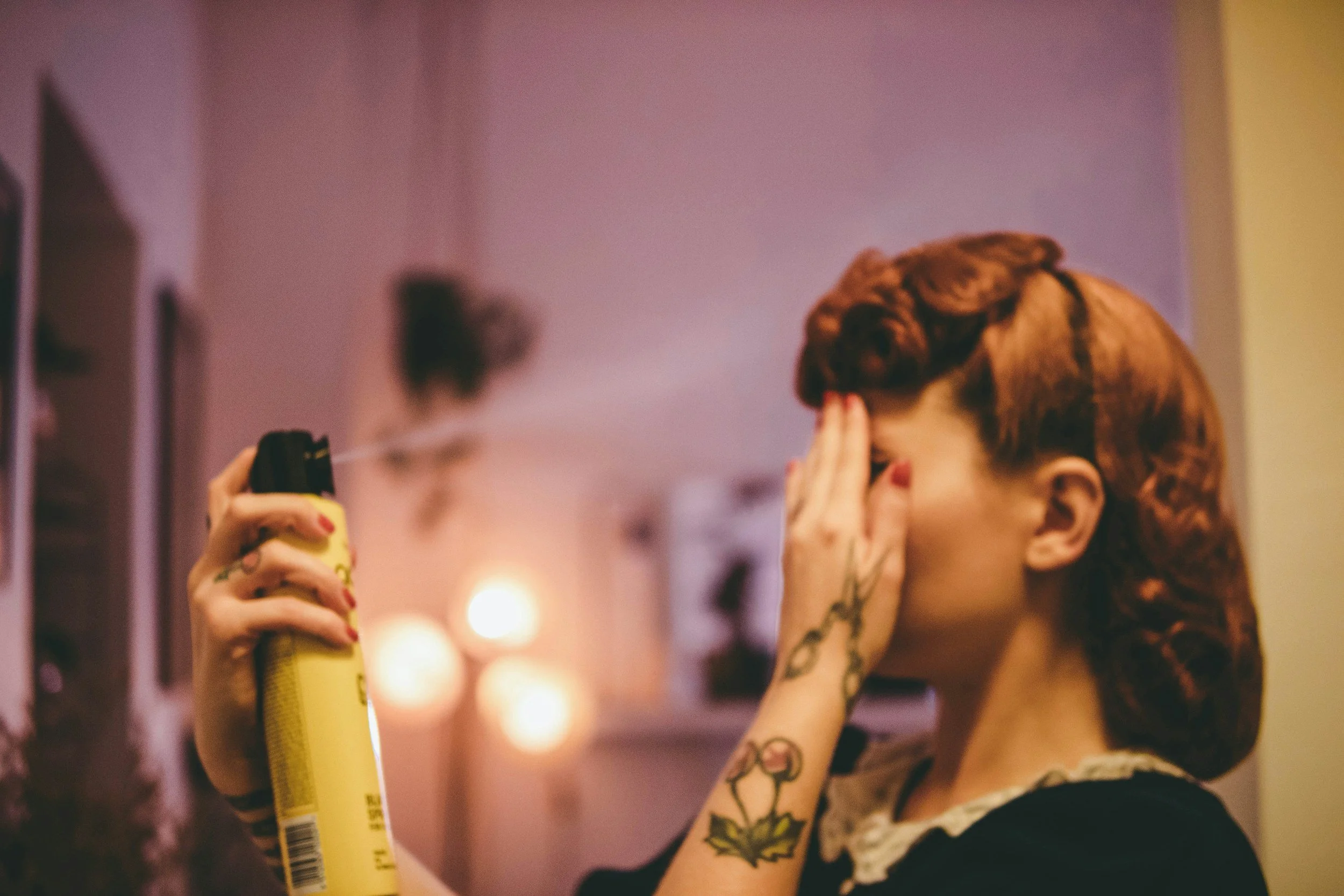 Woman spraying hair spray on styled hair