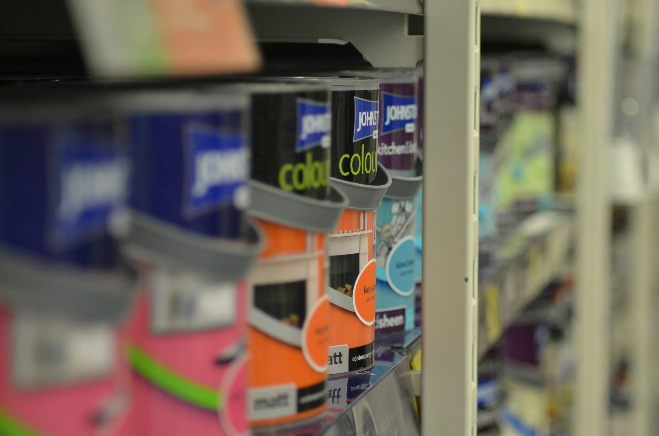 Paint cans lined up on shelf in hardware store