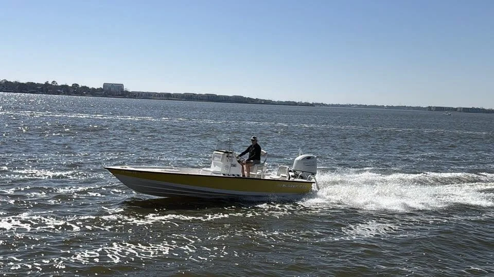 Man on fishing boat  in water with large building in background