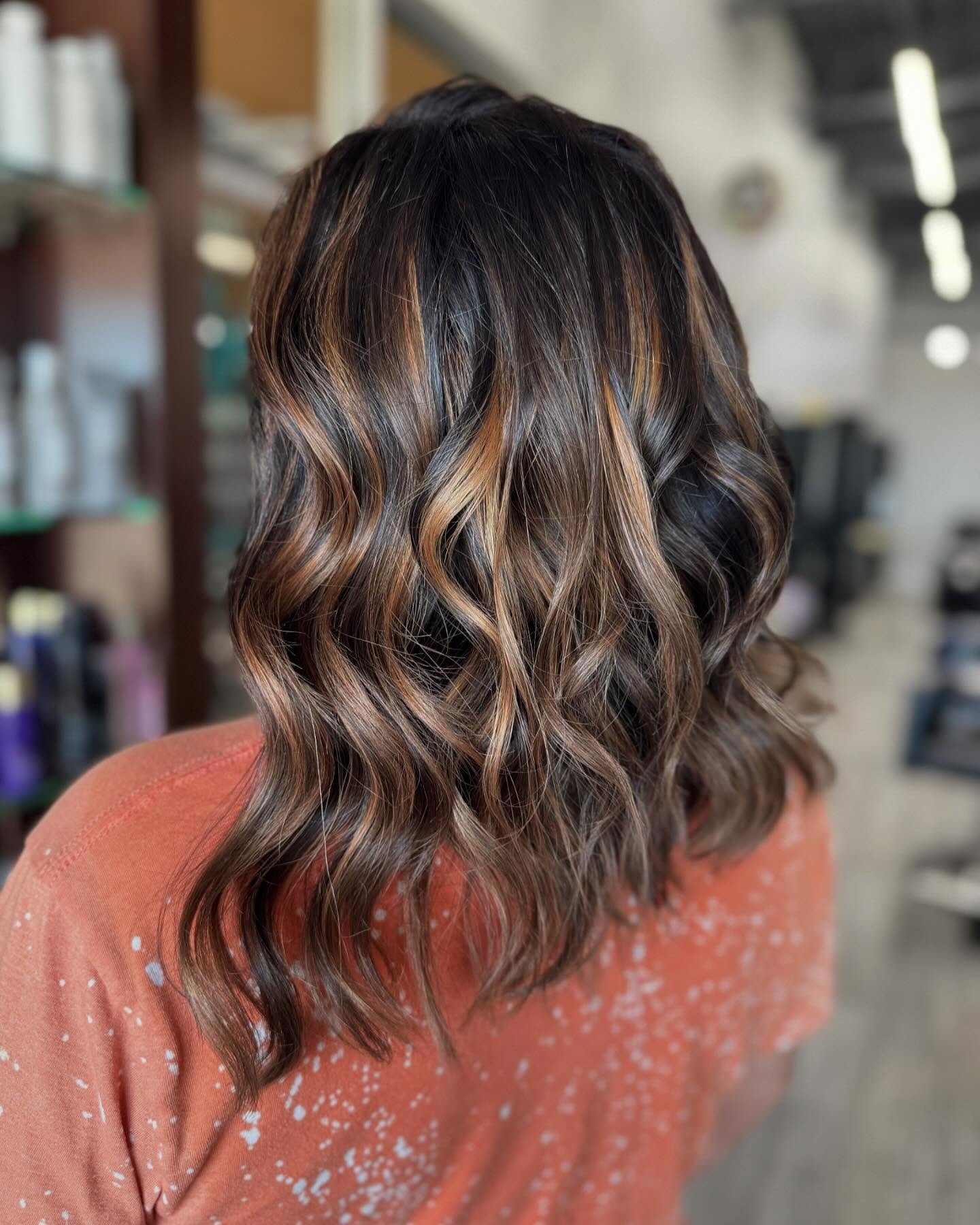 Brunette woman showing highlights and curls on back of head after getting hair styled