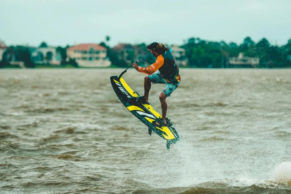 Man in mid-air is steering a mororized surfboard
