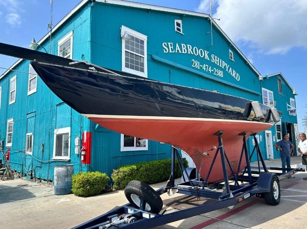 Blue shipyard building with orange and black hull visible in front