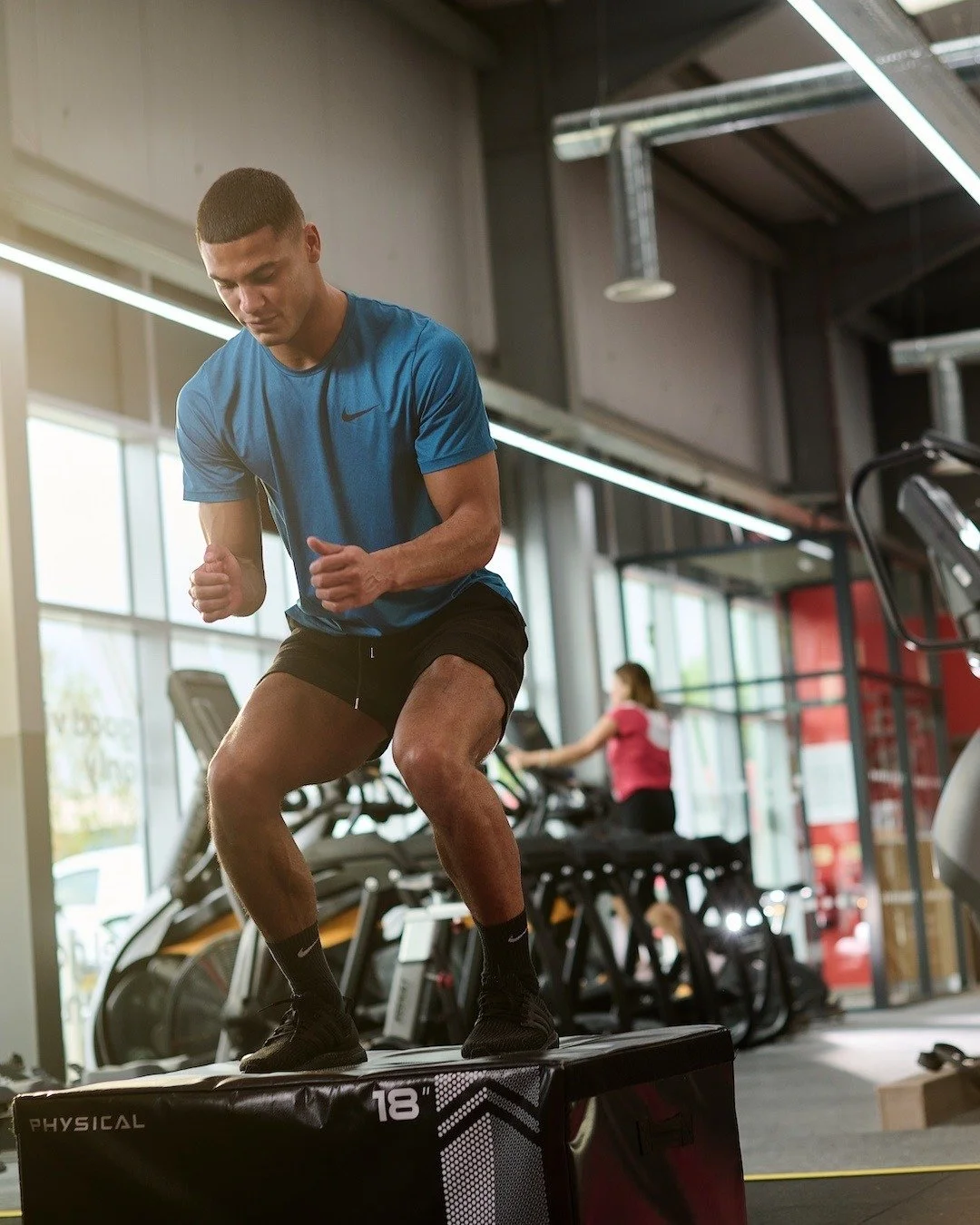 Man in blue shorts black shorts exercising in a gym