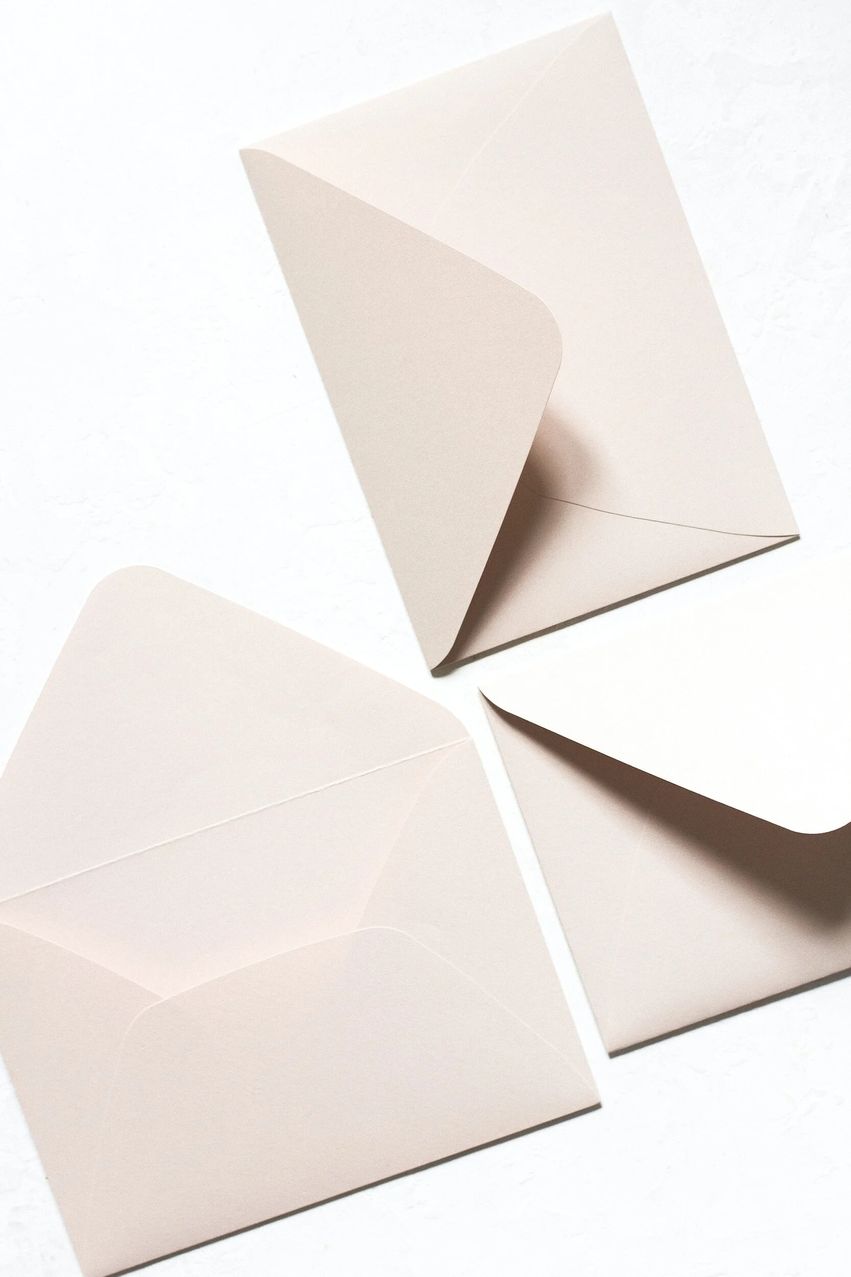 Three blank, cream-colored envelopes on a white surface.