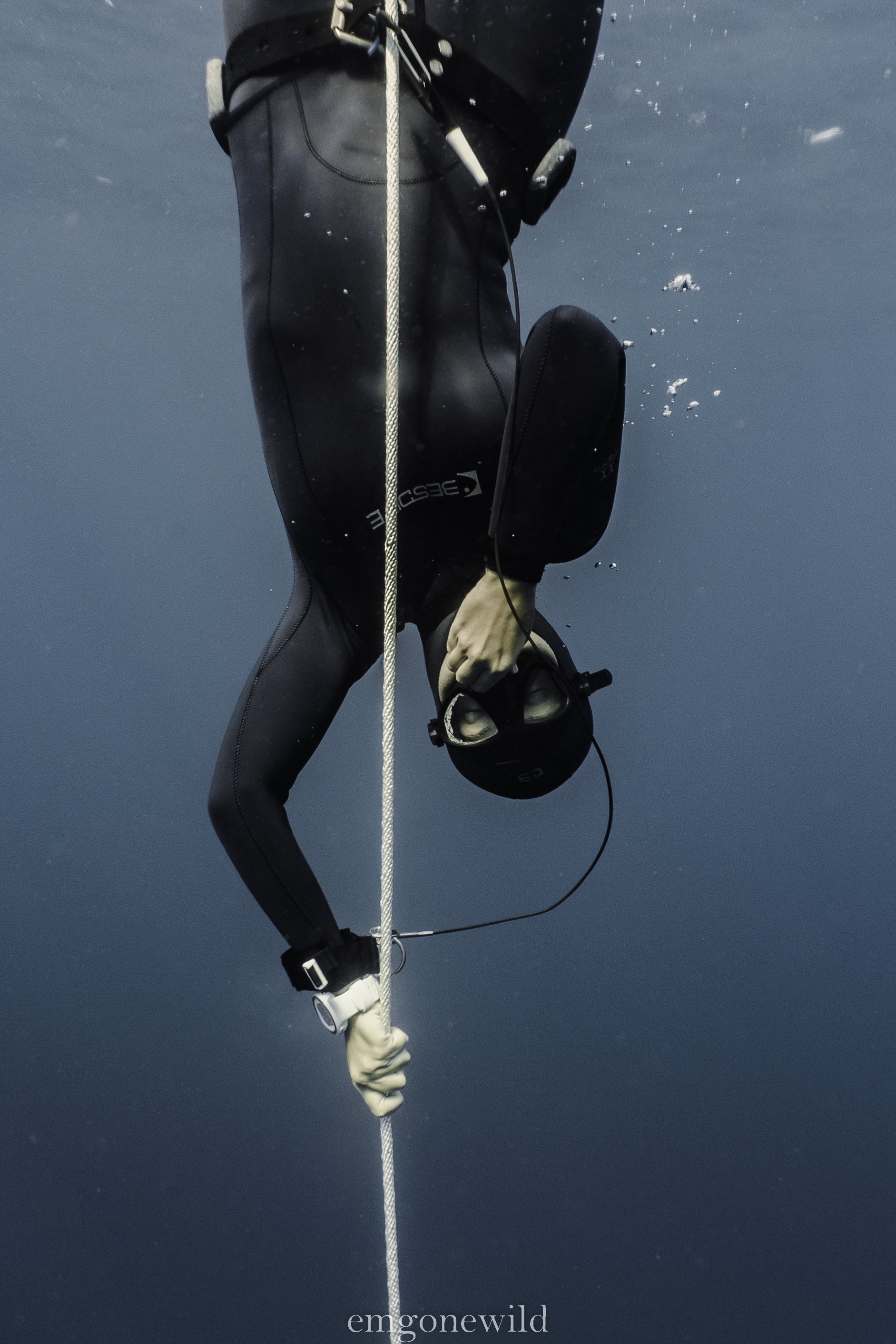 Freediver descending underwater holding a rope