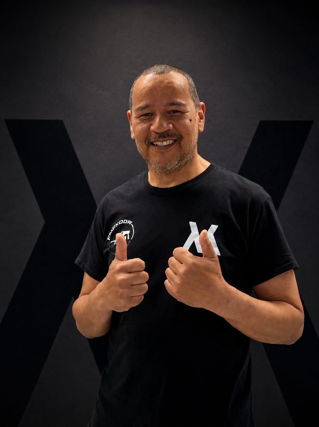 Coach Brian Kum in black t-shirt giving two thumbs up.