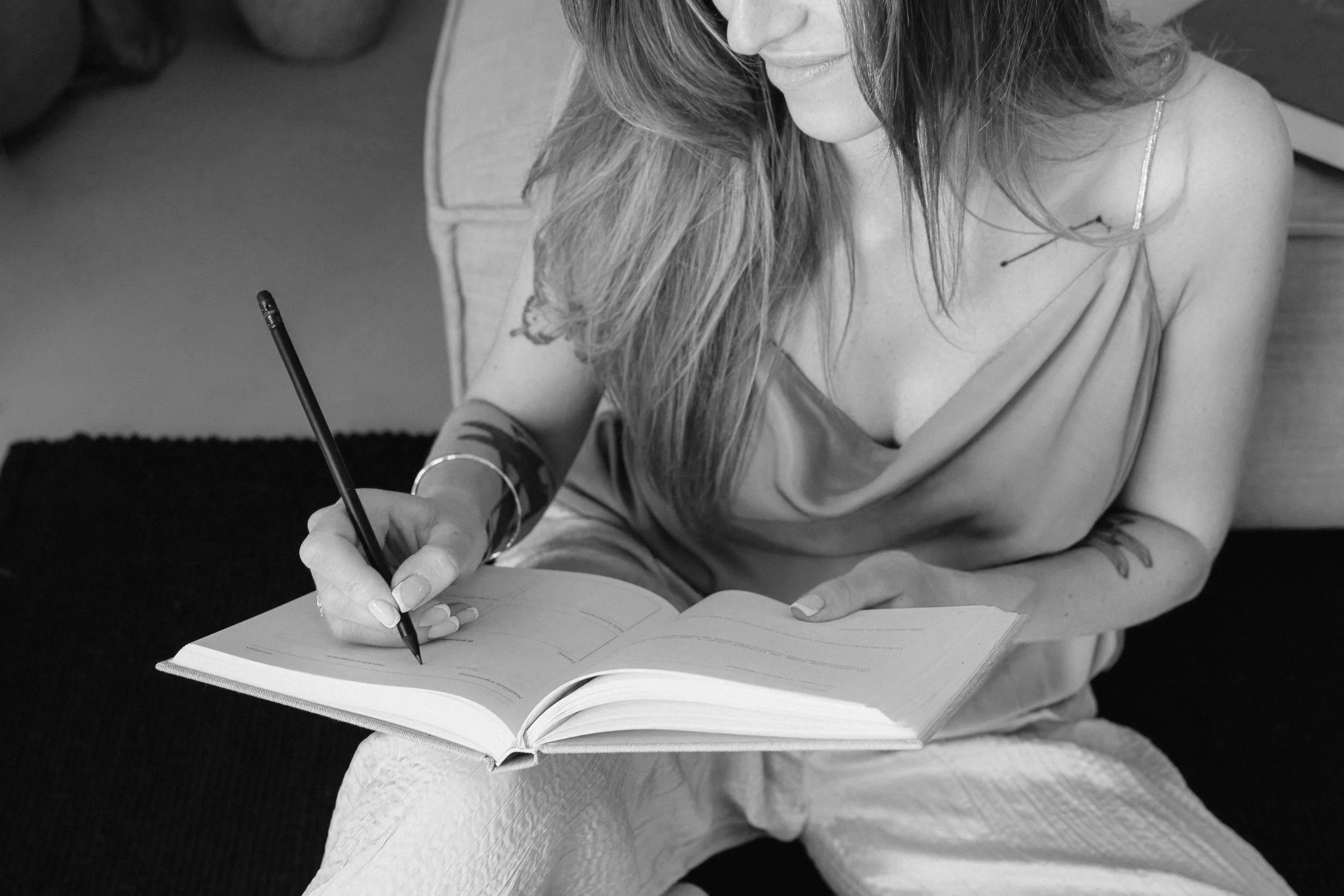 Close up of a woman smiling and writing in a notebook.
