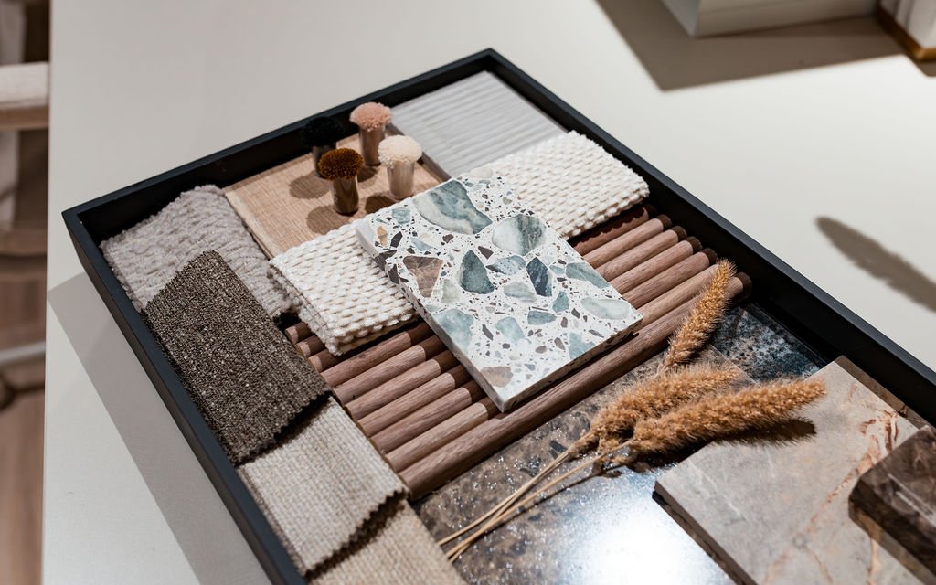 A black tray full of tiles and fluted materials. Stone and fabrics in neutral colours