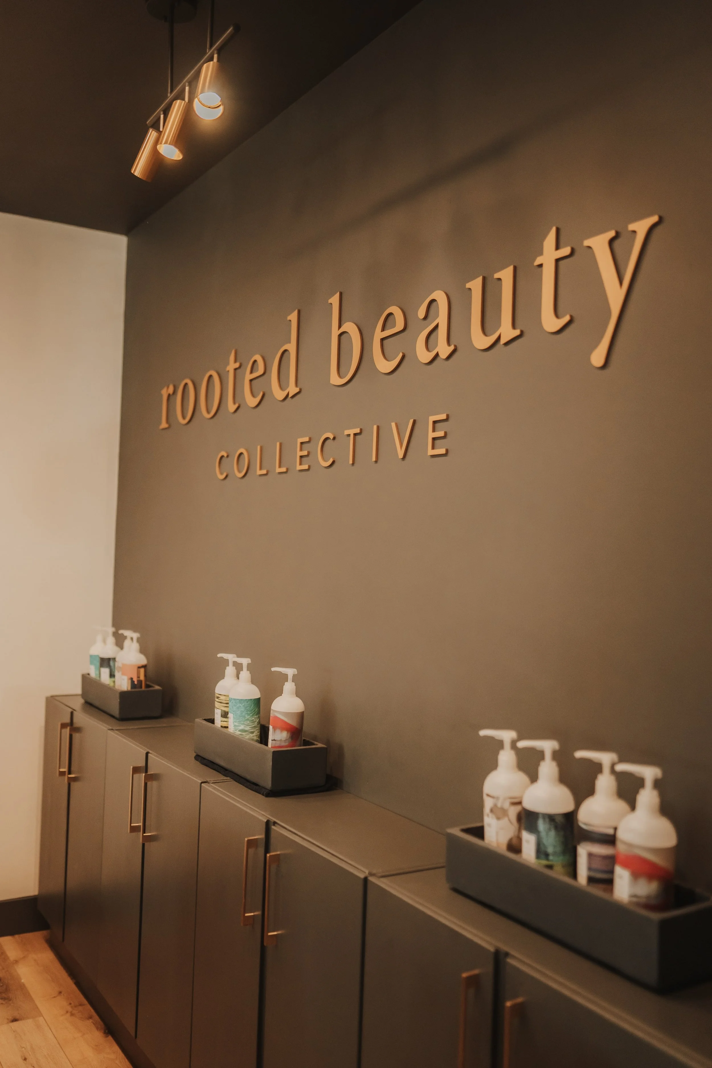 Interior of Rooted Beauty Collective, featuring a modern wall design with product shelves below, displaying various skincare bottles.