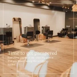 Interior view of a modern hair salon with styling chairs, mirrors, and hair products. Text overlay reads: 'Time to get pampered. Every time you sit in my chair my goal is that you leave feeling like a million bucks!'