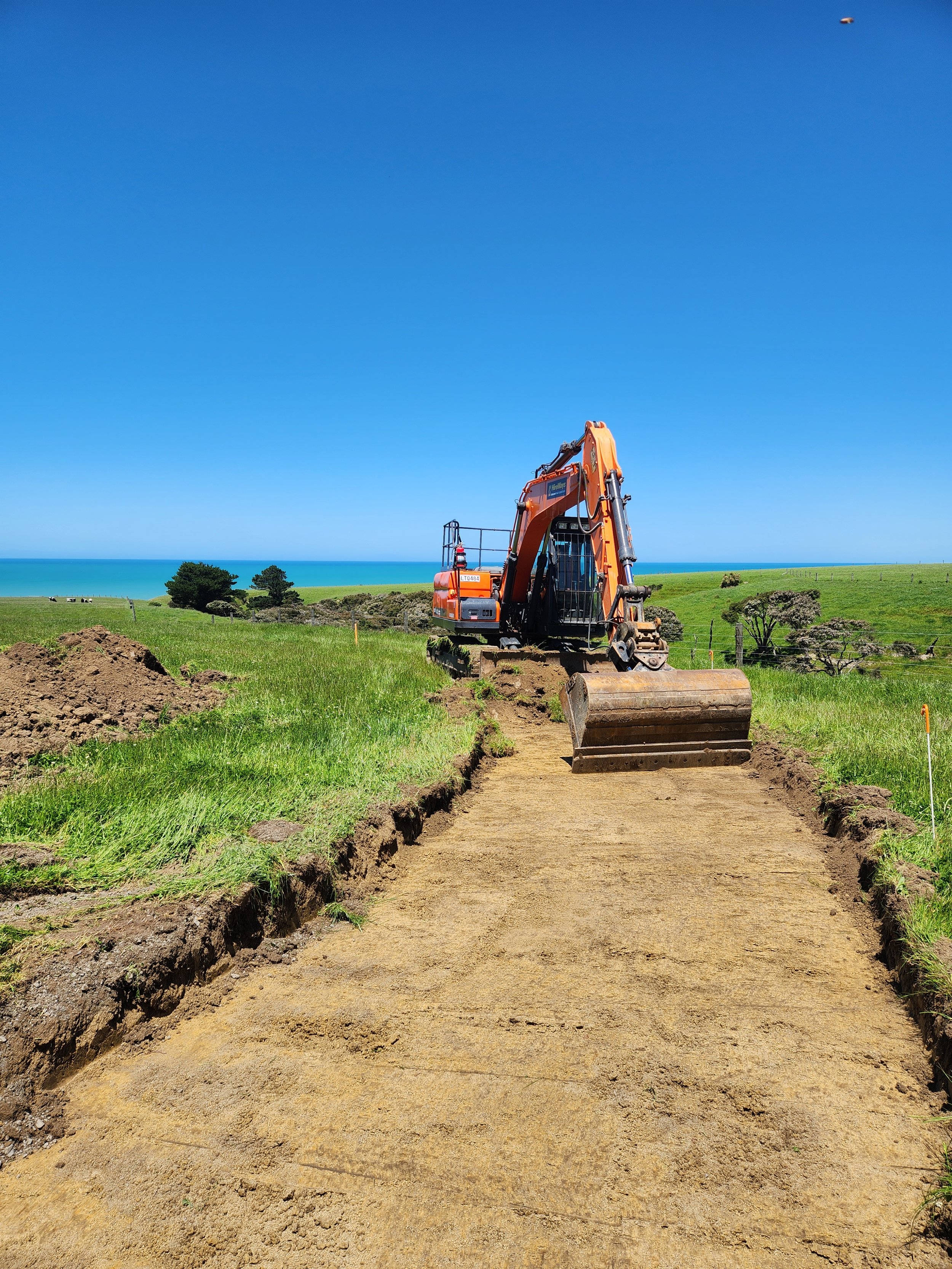 excavator creating an accessway by stripping topsoil prior to spreading metal on  a lifestyle property