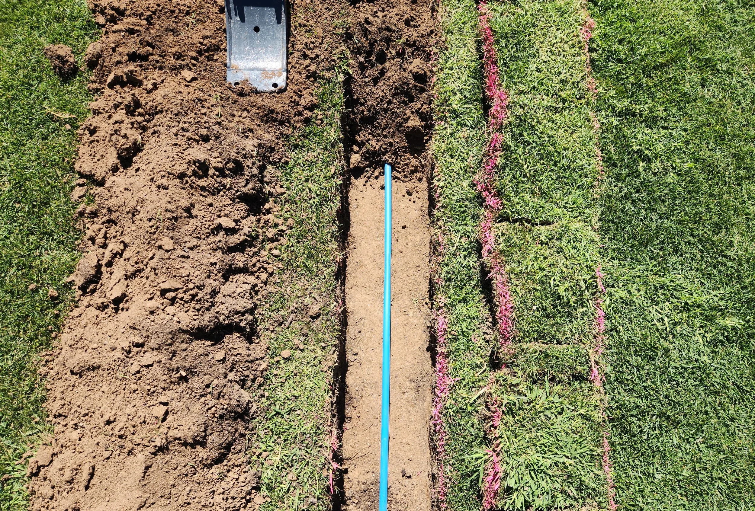 an excavator trenching a telecomunications trench on a residential house site