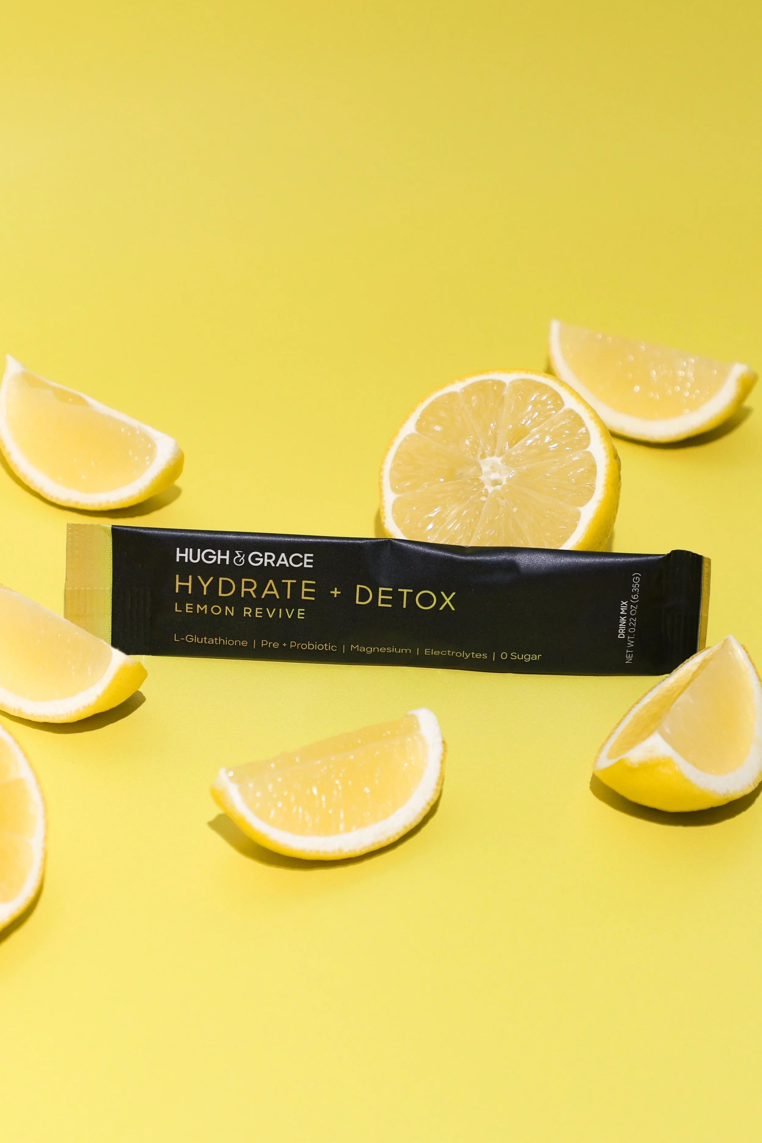 A black packet of Hugh & Grace hydrate + detox Lemon Revive drink mix. Commercial product photography for CPG, food, and beverage brands, creating e-commerce, social media, and marketing-ready product images.